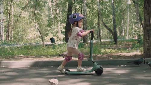 Girl 3 Years Old Rides a Scooter in Protective Clothing