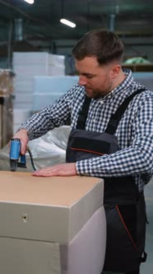 Man Stapling Upholstery Fabric on Sofa Base