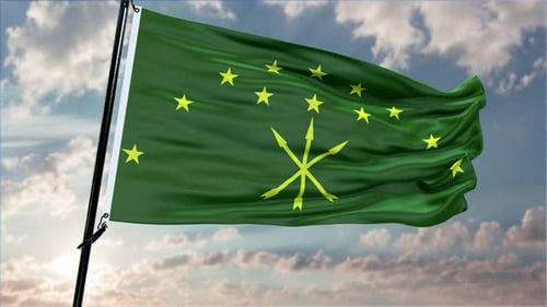 Green Flag with Yellow Stars Waving in a Cloudy Sky