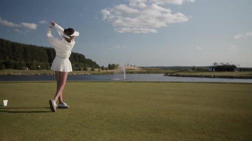 Woman Swinging Golf Club on Sunny Golf Course