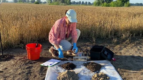 Female Scientist Testing Soil Sample Outdoors Using Lab Equipment