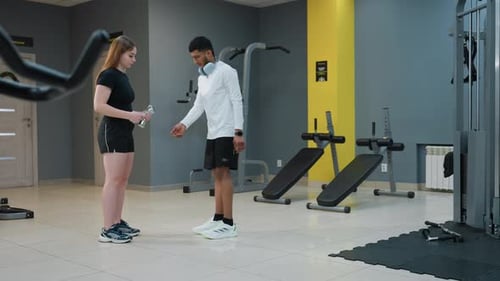 Man Hands Dumbbell to Woman During Gym Training Session for Stamina Development