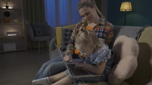 Side View of a Mom Teaching Her Daughter How to Use Computer Applications Mom and Daughter Sitting