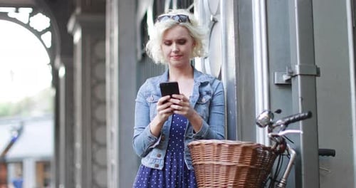 Woman Using Mobile Phone Near Bicycle in City
