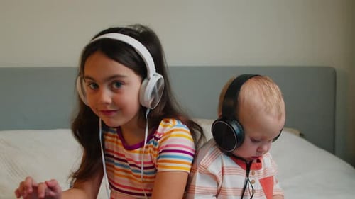 Girl and Baby Listen to Music on Headphones