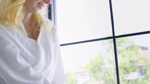 Woman in Robe Sprays Water in Hands