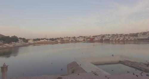 Une belle photo d'établissement du lac Pushkar au lever du soleil, heure d'or, avec des oiseaux qui volent, a été prise