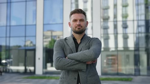 Portrait of Handsome Young Caucasian Businessman Standing Outside Near Business Center Crossing His