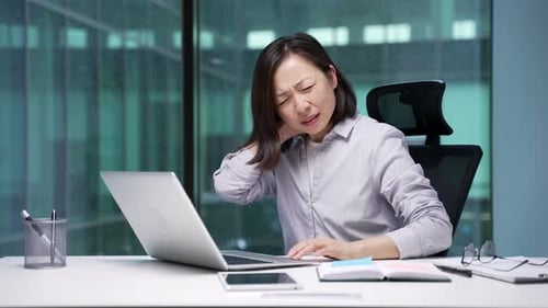 Woman Working at Desk Massaging Neck in Pain