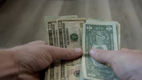 Hand counting cash, unfolded US dollar bills being counted by hand. Counting money