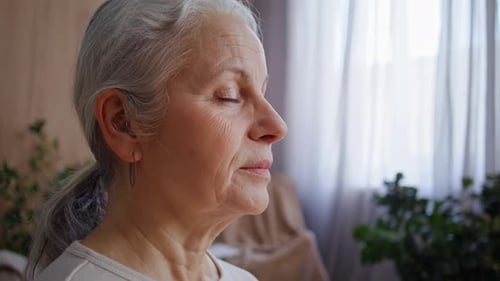 Senior Woman with Gray Hair Meditating Indoors Peacefully