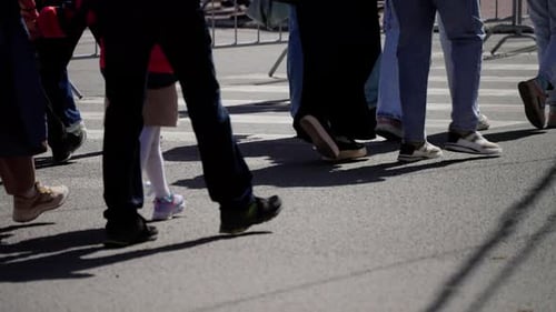 Candid Capture of Various Pedestrians Crossing a City Street Showcasing a Mix of Footwear and Styles