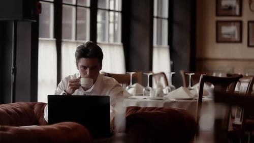Man Working on Laptop with Coffee in Restaurant