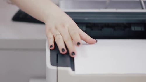 Die Person entnimmt Ausdrucke aus dem Drucker