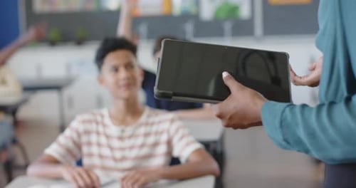 In school, boy raising hand in classroom, engaging with teacher
