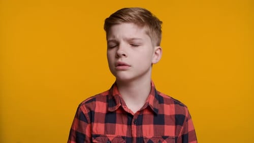Niño sacudiendo la cabeza diciendo «No, no, no» sobre fondo amarillo