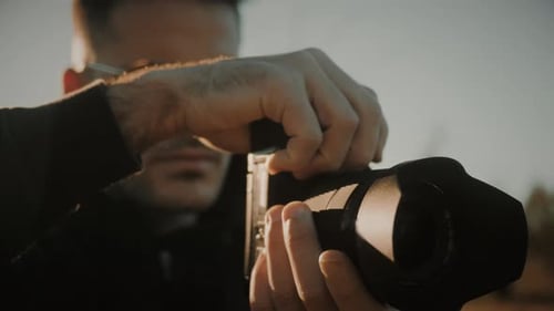 Man Adjusting Settings on Professional Camera at Sunset