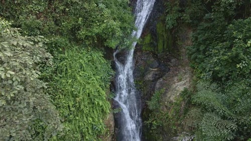Ascending drone shot waterfall hidden in tropical rain forest jungle,