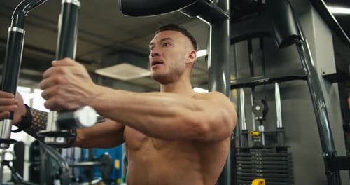 A Focused Athlete Flexes His Arm Muscles on the Exercise Machine Working Out Every Arm Muscle in the