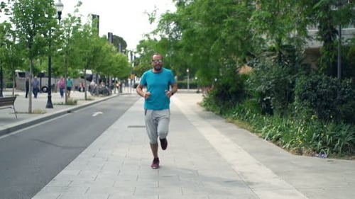Handsome young man jogging in the city training for a marathon in super slow motion