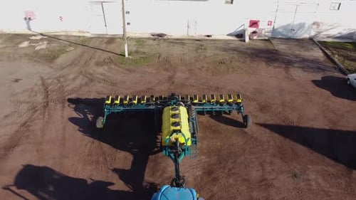 Blue tractor with yellow seeder working on the field in Ukraine OA