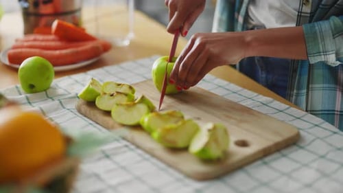 Woman cutting green apple on wooden cutting board