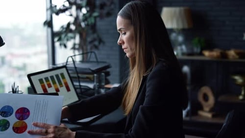 Businesswoman Analyzes Charts and Graphs at Office Desk