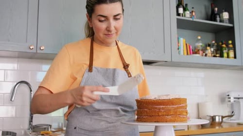 Woman Frosting Layer Cake in Kitchen