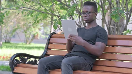 Young Adult Using Tablet on Park Bench