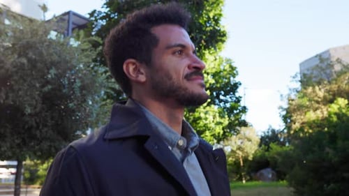 Confident Young Businessman Walking Outdoors in a City Park