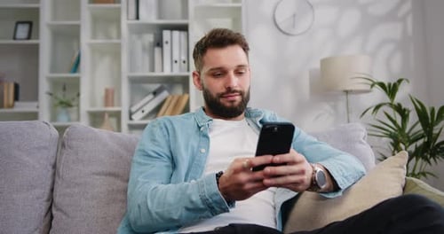 Man Relaxing on Couch with Smartphone