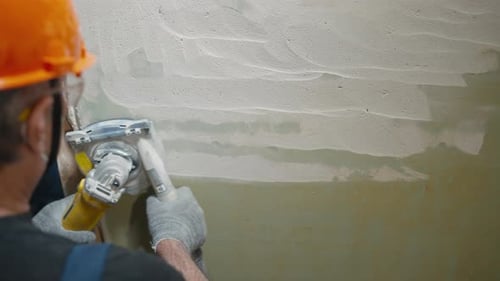 Construction Worker Sanding Interior Wall with Power Tool