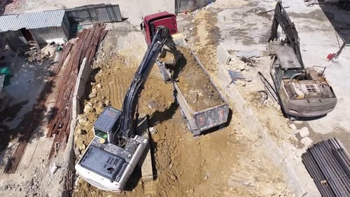 Excavatrice chargeant de la terre dans un camion à benne basculante sur un chantier de construction