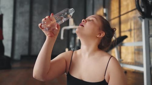Woman Drinks Water After Workout at Gym