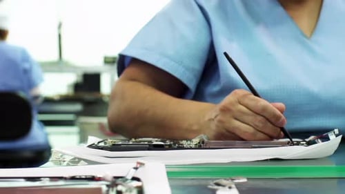 Trabajadoras instalando hardware en una línea de ensamblaje de computadoras portátiles - 4K
