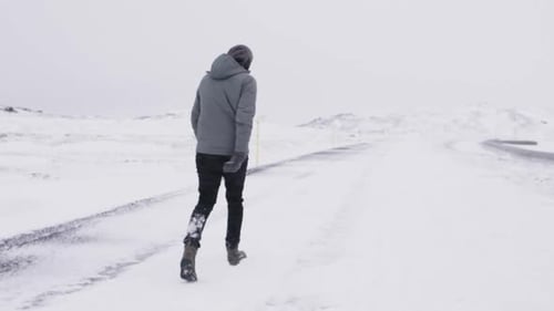 Junger männlicher Reisender geht in Zeitlupe durch den Schneesturm