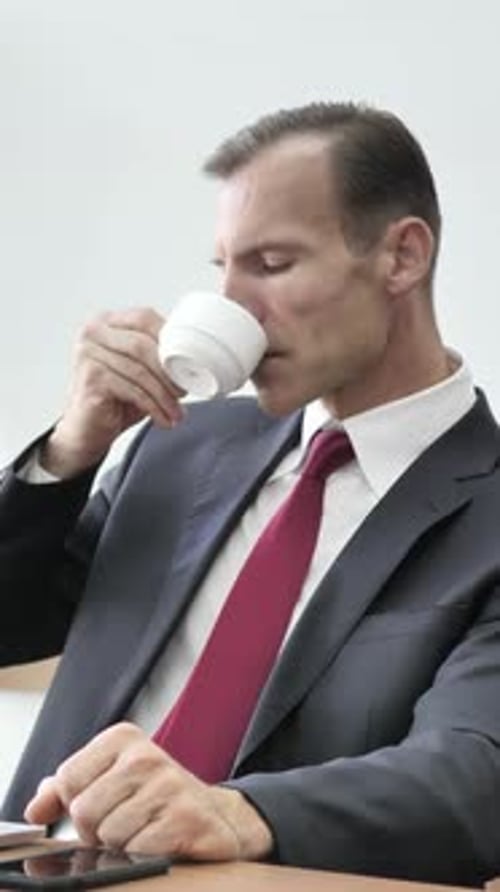 Confident Businessman Drinks Coffee in Minimalist Office