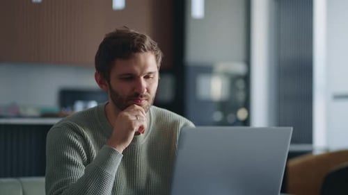 Young Adult Man Concentrating on Laptop Indoors