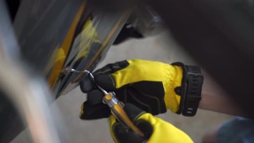 Mechanic's gloved hands seen tightening a bolt on the body or his beloved motorcycle - close angle l