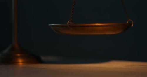 Scales of justice on table in darkness, closeup