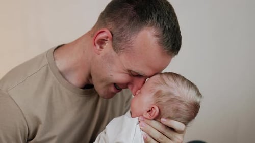 Dark Haired Adult Holding Infant in Arms
