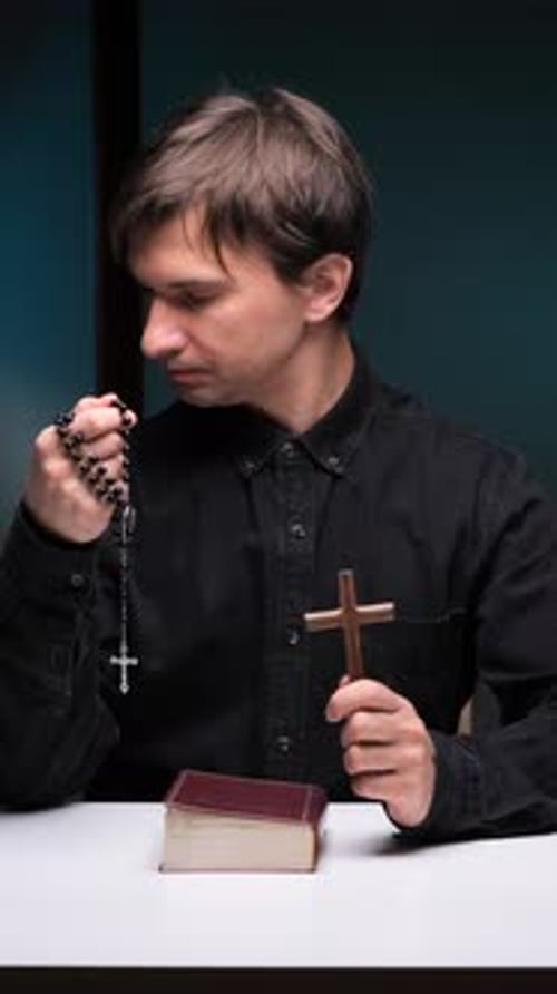 Person Holding Rosary and Cross Praying Indoors