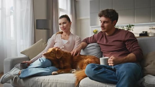 Relaxing Couple Petting Dog on Cozy Sofa