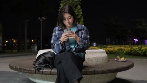 Young Woman Using Phone in Park at Night