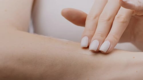 Adult Hand Applying Cream to Skin Close Up