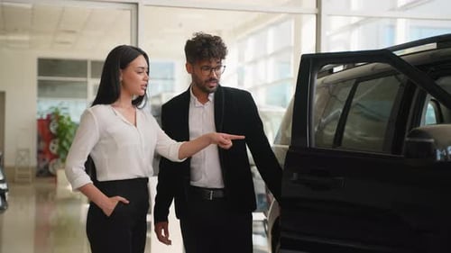Car Saleswoman Showing Features of New Vehicle to Customer