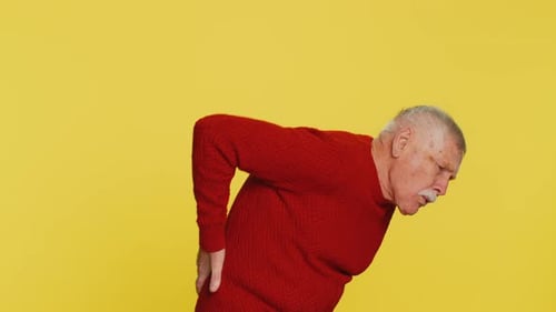 Senior Man with Back Pain Against Yellow Background