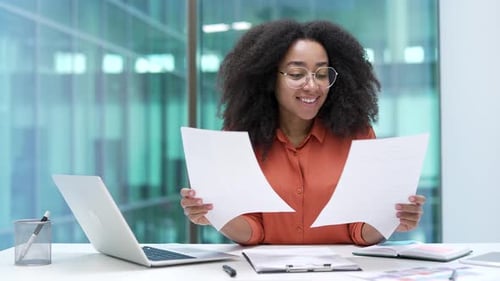 Happy Woman Reviews Documents at Workplace