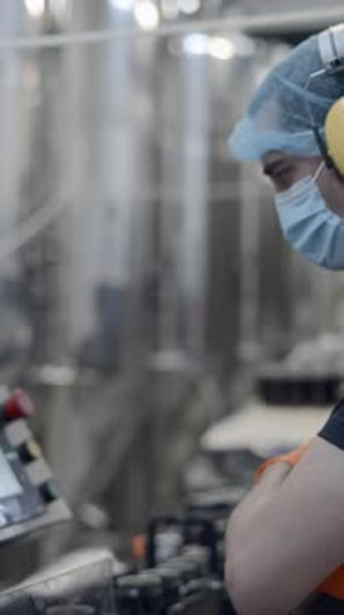 Factory Worker Operating Conveyor With Beer Cans Moving Medium Shot