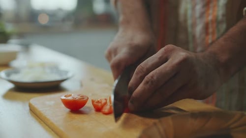 Close-Up of Hands of Chef Cutting Fresh Tomato at Kitchen Countertop